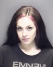 a mugshot of a woamn with a beautiful smile and pink hair