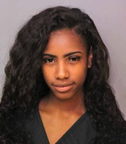 mugshot of a hot looking woman with curly long hair and pretty smile