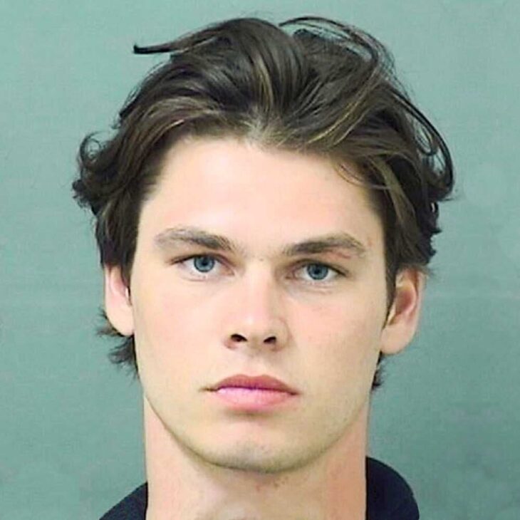 a police photo of a hot looking guy with blue eyes and wavy hair